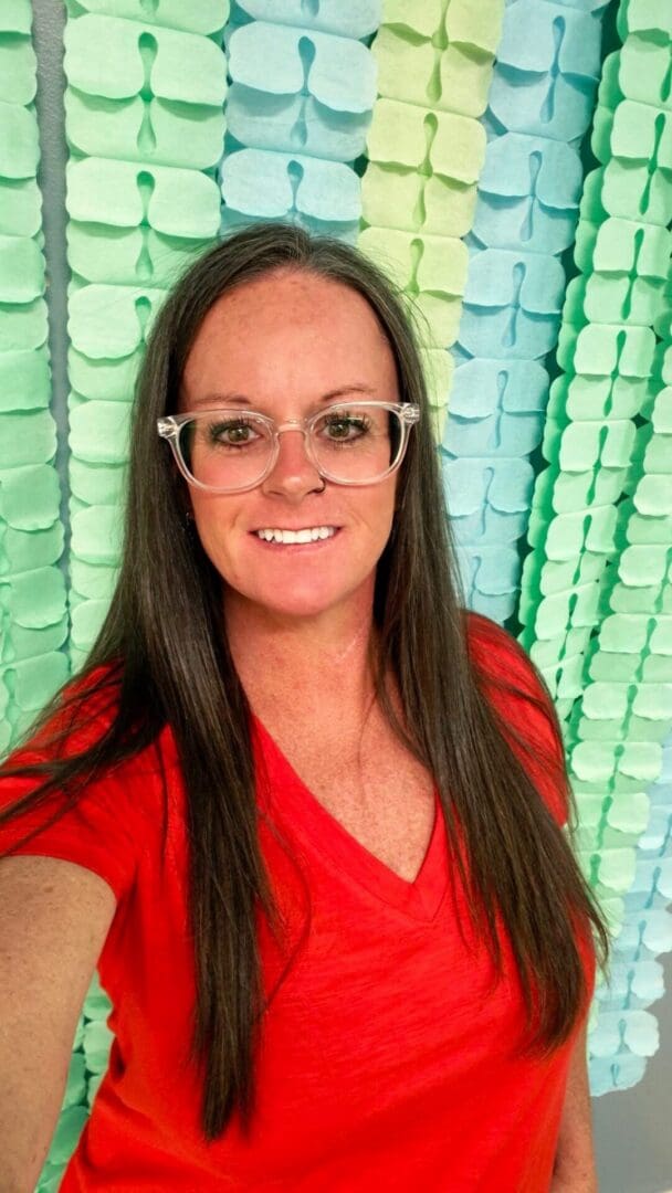 Smiling woman in red shirt against colorful backdrop.